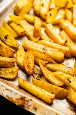 Sliced grilled potatoes with spices and herbs on the pan. Selective focus. Shallow depth of field.
