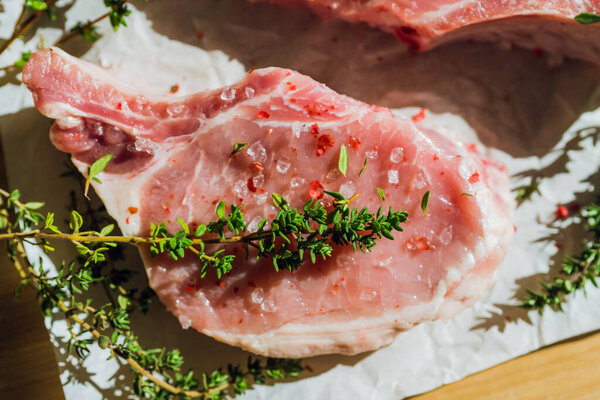 Сырое мясо свинины с тимьяном и специями на деревенском фоне. Выборочный фокус. Мелкая глубина резкости.