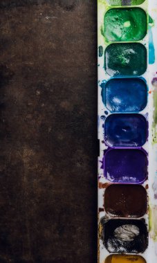 Sanatsal fırça ve suluboya boyalarla dolu beyaz plastik bir kap. Yukarıdan ateş edildi.