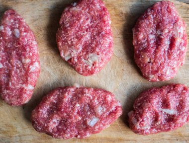 Eski ahşap kesme tahtasının üzerinde kıyma yapılmış çiğ pirzola. Seçici odaklanma. Ülke biçimi.