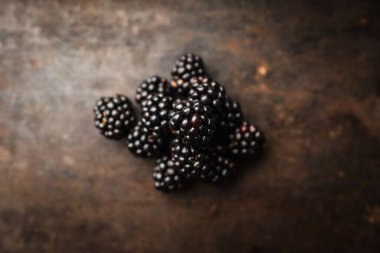 Koyu kırsal arka planda olgun böğürtlen yığını. Seçici odaklanma. Sığ alan derinliği.