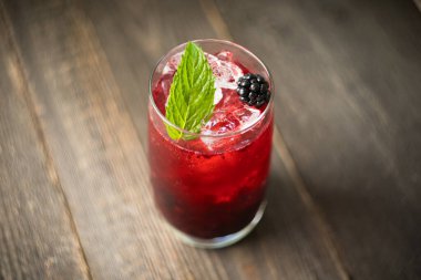 Kırsal ahşap arka planda ezilmiş buzlu böğürtlen kokteyli. Seçici odaklanma. Sığ alan derinliği.