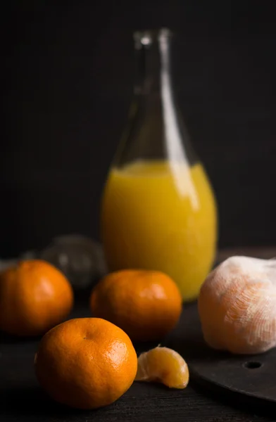Апельсины и сок на темном фоне — стоковое фото