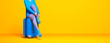 Kadın kısa elbisesi valiz tekerlerinde oturur. Kadın çorapları bacaklar arka plan boyası. Kadın fotoğraf stüdyosu. Kavramsal moda sanatı.