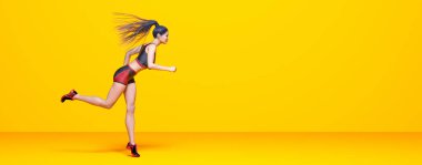 Kadın atlet koşu, bikinili şort. Pastel duvar arka planı. Kadın stüdyo fotoğrafı. Kavramsal moda sanatı.