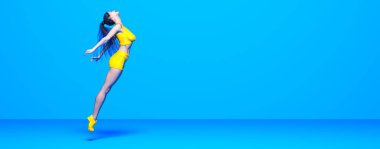 Kadın atlet koşu, bikinili şort. Pastel duvar arka planı. Kadın stüdyo fotoğrafı. Kavramsal moda sanatı.