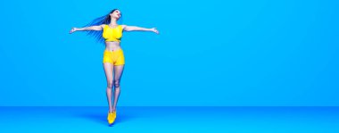 Kadın atlet koşu, bikinili şort. Pastel duvar arka planı. Kadın stüdyo fotoğrafı. Kavramsal moda sanatı.