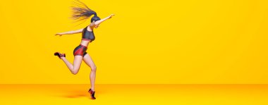 Kadın atlet koşu, bikinili şort. Pastel duvar arka planı. Kadın stüdyo fotoğrafı. Kavramsal moda sanatı.