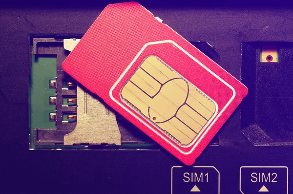 Red Sim karta na sloty v mobilním telefonu. — Stock fotografie