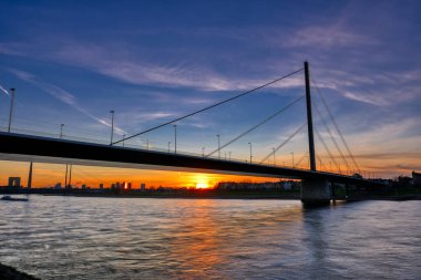 Düsseldorf 'ta gün batımında Ren nehri boyunca köprü.