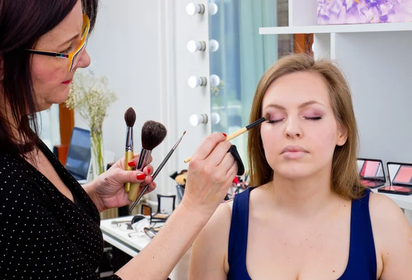 Maquillaje artista aplicar sombra de ojos en los ojos de las mujeres —  Fotos de Stock