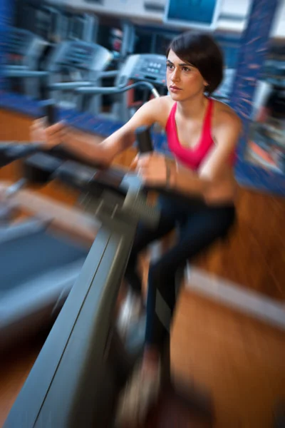 Vrouw in sportschool op fiets — Stockfoto