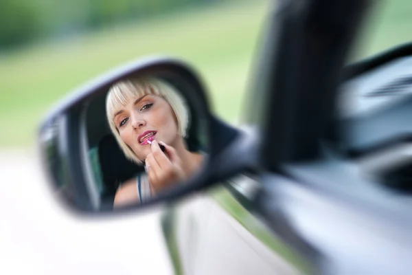 Woman driver putting lipstick — Stock Photo, Image