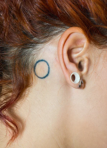 Oreille de fille avec piercings et tatouage — Photo