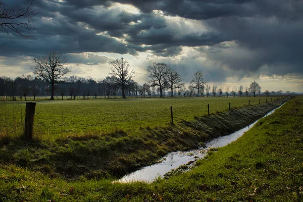 Fırtına sırasında tarlaları ve ağır bulutları olan Hollanda manzarası
