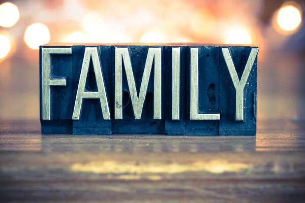 The word FAMILY written in vintage metal letterpress type on a soft backlit background.