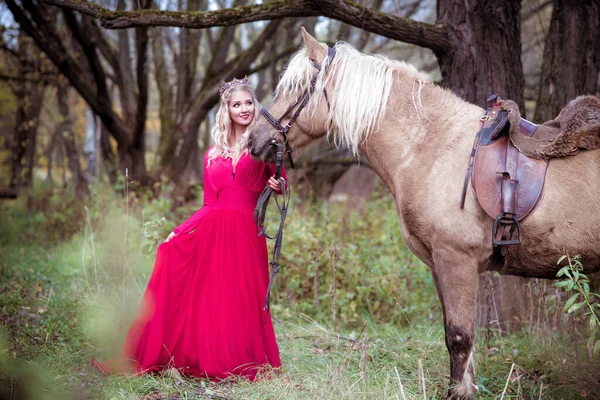 Beautiful woman in crown, blonde with horse. Princess in fairy tale. Fantasy autumn