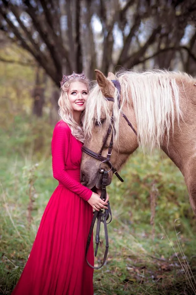 Beautiful woman in crown, blonde with horse. Princess in fairy tale. Fantasy autumn