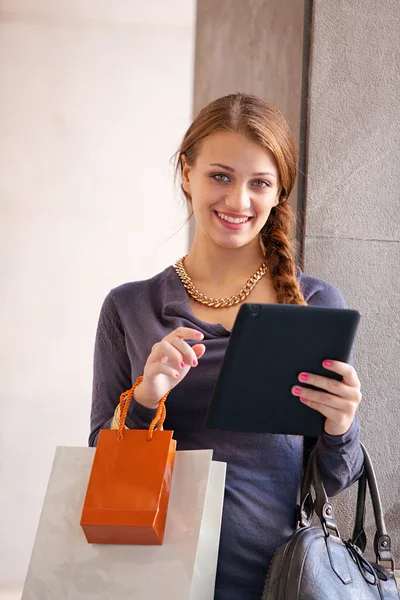 Kobieta z torby na zakupy i cyfrowy tablicowy — Zdjęcie stockowe