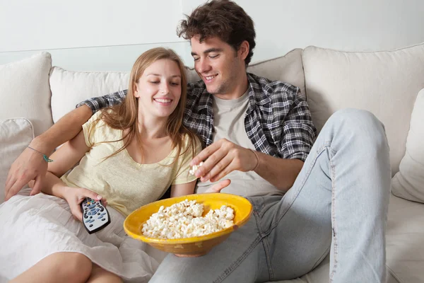 Casal assistindo televisão, comendo milho pop — Fotografia de Stock