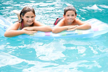 children swimming together in a blue pool