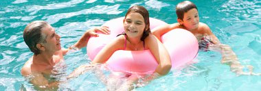family swimming together in a pool