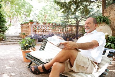 man sitting on a bench and reading a newspaper