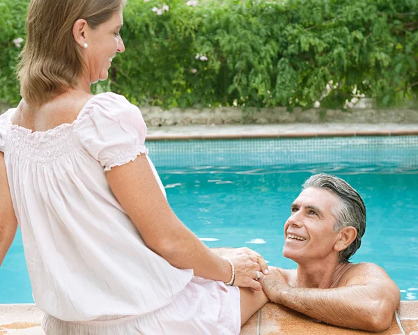 Couple relaxing together on the egde of a swimming pool — 스톡 사진