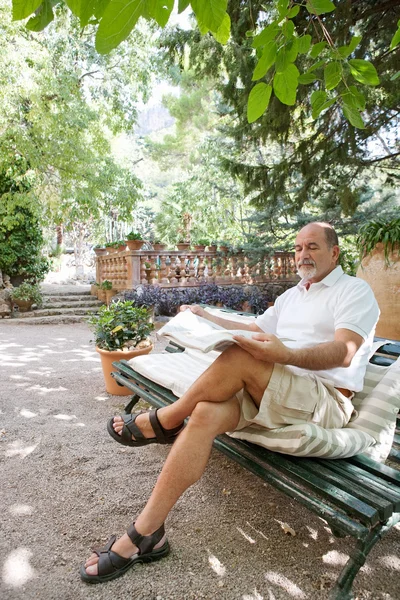 man sitting on a bench and reading a newspaper