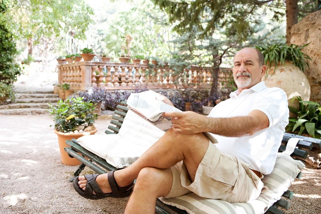 man sitting on a bench and reading a newspaper
