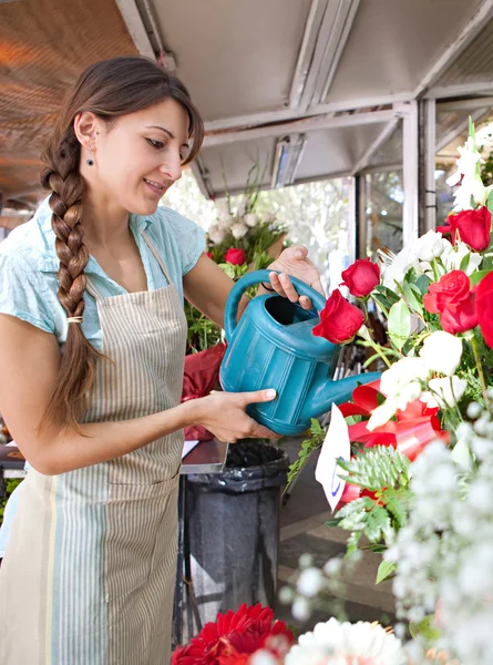 Mujer florista regando las plantas y flores en su tienda —  Fotos de Stock