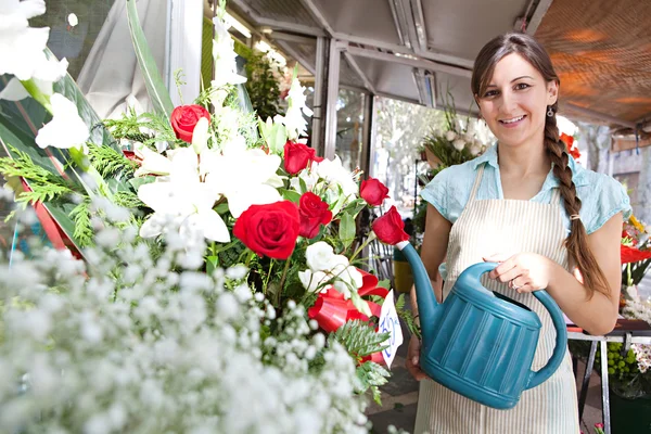 Florista mulher regando as plantas e flores em sua loja — Fotografia de Stock