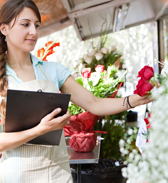 Florista mujer trabaja en su tienda con un portapapeles — Foto de Stock