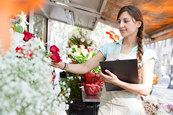 Florista mujer trabaja en su tienda con un portapapeles —  Fotos de Stock