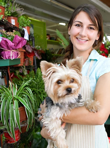Florista mujer sosteniendo un perro en su tienda — Foto de Stock