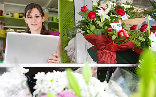 Fiorista donna utilizzando un computer portatile nel suo negozio — Foto Stock