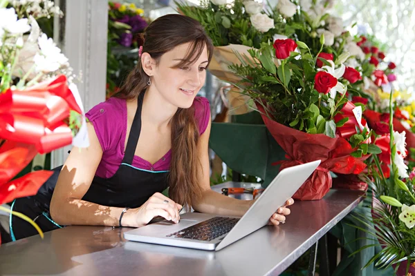 Цветочница использует ноутбук в своем магазине — стоковое фото