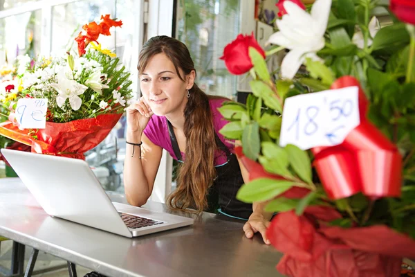 Florista mulher usando um laptop em sua loja — Fotografia de Stock