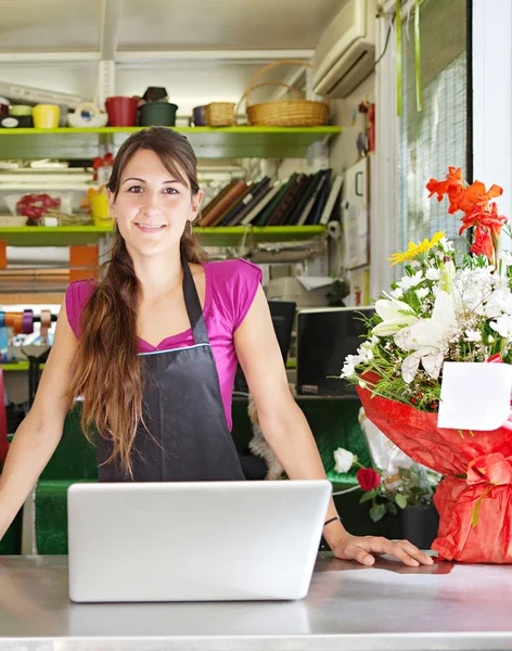 Florista mulher usando um laptop em sua loja — Fotografia de Stock