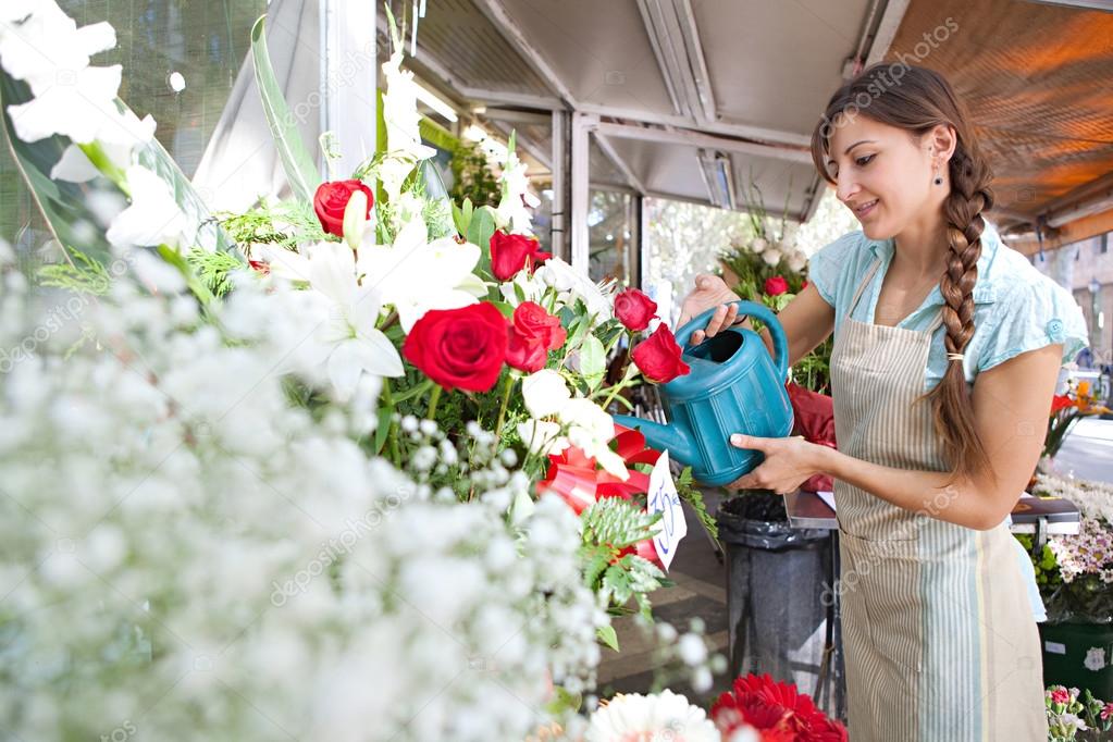 florist woman watering the plants and flowers in her store