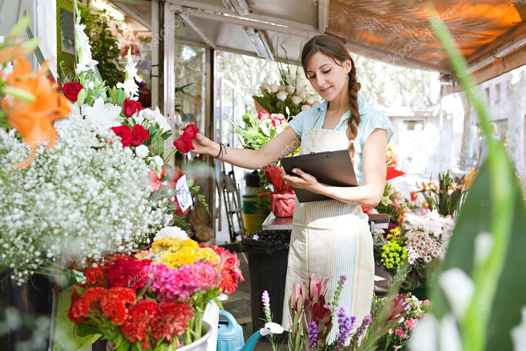 florist woman works in her store with a a clipboard