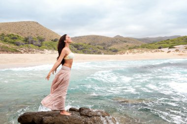 woman standing on a rock by the sea