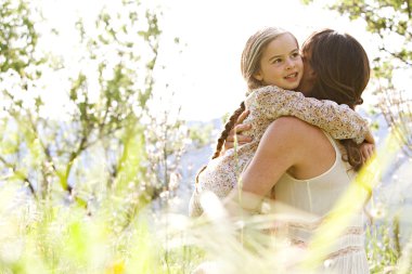 Mother and daughter hugging in a spring field