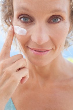 woman applying face cream on her skin