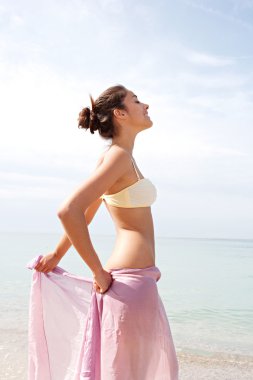 young woman with a pink fabric sarong on the beach