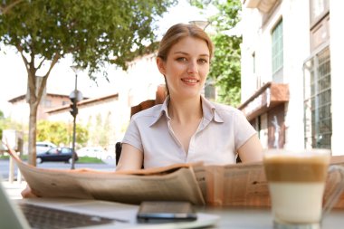 businesswoman reading a financial newspaper and drinking a hot beverage