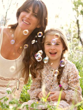 mother and daughter playing to blow floating bubbles