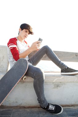 boy with a skateboard using a smartphone