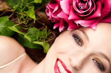 woman laying in a forest wearing a red roses head dress