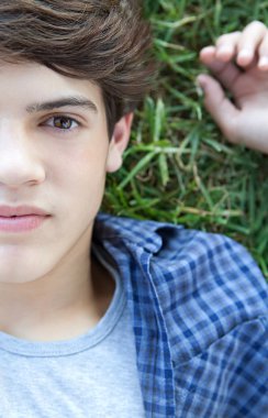 boy laying down on  grass in a park